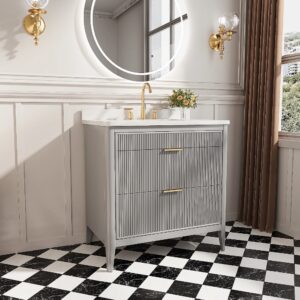 A modern bathroom features the Aveline 36 Inch Freestanding Bathroom Vanity with Top, gray fluted front, gold faucet, round mirror, wall sconces, small flower vase, black-and-white checkered tile floor, white wainscoting, and a window.