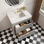 The Aveline 36 Inch Freestanding Bathroom Vanity With Top features a white countertop, gold faucet, under-mount sink, two open drawers for towels and toiletries, and is paired with a round mirror and black-and-white checkered floor.