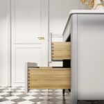 A close-up side view of the Aveline 36 Inch Freestanding Bathroom Vanity With Top shows two open wooden drawers, black-and-white checkered floor tiles, and a white door with a gold handle in the background.