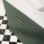 The Aveline 36 Inch Freestanding Bathroom Vanity With Top features a green finish with vertical grooves, gold handles, and a white marble countertop. The floor displays black and white checkered tile with marble-textured accents.