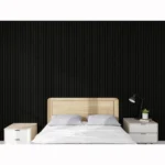 A modern bedroom featuring the Acoustic Interior Wall Panel in black as an accent wall, with a light wooden bed frame, white bedding, two white nightstands, a black desk lamp, and a small plant.