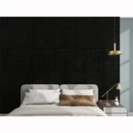 A modern bedroom features a beige bed with pillows, a side table and lamp, and the Acoustic Interior Wall Panel with a geometric grid of square panels. A gold pendant light above adds elegance to the space.