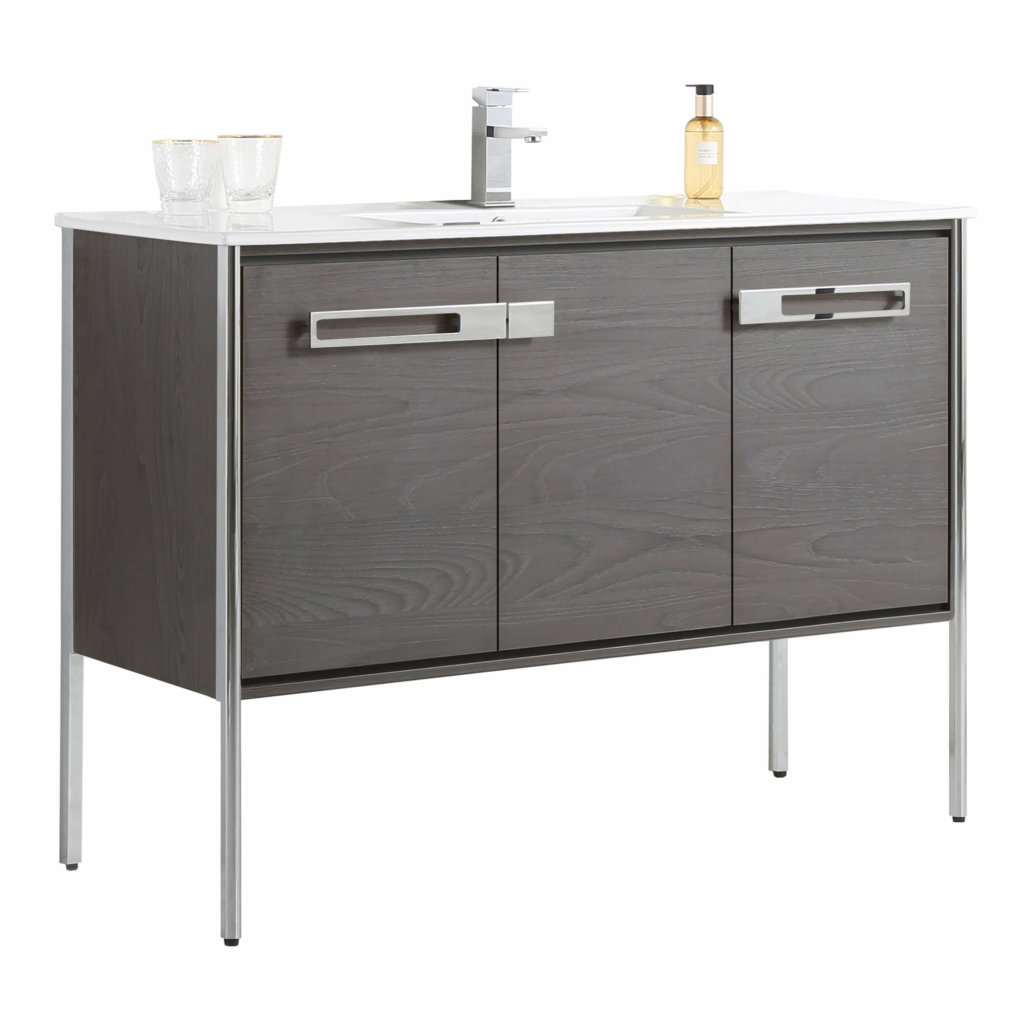 The Oakville 48 inch Modern Bathroom Vanity features a dark wood finish, metal legs, two cabinet doors with wide silver handles, a white countertop, and comes topped with a faucet, two glasses, and a soap dispenser.