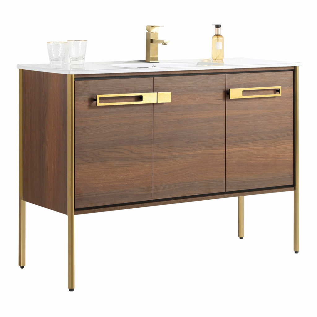 The Oakville 48 inch Modern Bathroom Vanity features a modern wood finish, gold metal legs and handles, a white countertop with integrated sink, gold faucet, two glasses, and a soap dispenser.