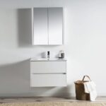 A modern bathroom features a floating Valencia 30 inch Wall Mount Vanity With Sink and a mirrored cabinet. A woven basket with a white towel on the floor complements the clean, minimalist design.