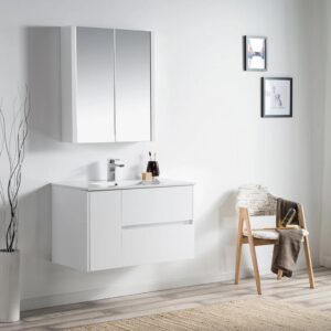 Minimalist bathroom with the Valencia 36 inch Wall Mount Vanity With Sink, a sleek mirrored cabinet, modern faucet, decorative vase with branches, towel-draped chair, and framed pictures against a crisp white wall.