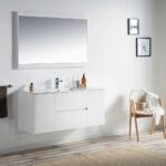 A modern bathroom showcases a large mirror above the Valencia 48 inch Wall Mount Vanity With Sink, paired with soap and lotion dispensers. To the right, a wooden chair with a cushion and towel sits atop light wood floors, accented by wall art.