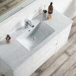 The Valencia 48 inch Wall Mount Vanity With Sink features a modern white sink, chrome faucet, soap dispenser, toothbrush holder, and soap bar on a white countertop atop a light wood textured floor.