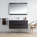 Modern bathroom with light walls and floors, large mirror above a Valencia 48 inch Wall Mount Vanity With Sink, single soap dispenser, towel on a wall rack, and a cushioned chair to the right for a sleek look.