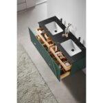 The Barcelona 60 Inch Wall Mount Double Bathroom Vanity With Top features two white square sinks, a black countertop, green cabinets with gold handles, organized open drawers with toiletries, and a beige textured rug on the floor.