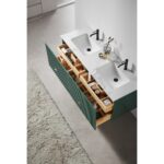 A modern bathroom features a Barcelona 60 Inch Wall Mount Double Bathroom Vanity With Top. The green drawers are open, displaying organized toiletries and accessories. A textured rug lies on the light gray floor.