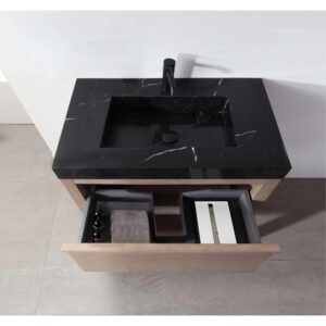 The Bibury 36 Inch Bathroom Vanity with Top features a sleek black marble sink, black faucet, and an open wooden drawer below with organized compartments holding bottles, a towel, and a rectangular box.