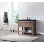 Modern bathroom featuring a Bibury 36 Inch Bathroom Vanity with Top, black sink, open shelf with towels, freestanding bathtub, ladder towel rack with dark towels, potted plant, bottles, and a light gray rug.