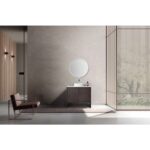 Minimalist bathroom featuring the Celle 36 Inch Bathroom Vanity With Vessel Sink topped with a round mirror, a modern chair on the left, and a large window with vertical wooden slats letting in natural light.