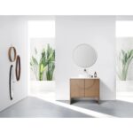 A minimalist bathroom with the Celle 36 Inch Bathroom Vanity With Vessel Sink, a round mirror above, a bottle atop the wooden vanity, and three wall-mounted circular mirrors to the left. Large windows let in natural light and showcase greenery outside.