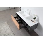The Goreme 48 Inch Wall Mount Bathroom Vanity With Vessel Sink includes a white countertop, rectangular sink, open drawer with organized compartments, and is shown with a brush and potted orchid on gray tile flooring beside part of a rug.