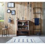 A cozy bathroom with wooden walls includes a Lyon 30 Inch Bathroom Vanity with Top, a rug, small cabinet for storage, black towel rack, hanging lights, framed art, stool with soap bottles, and a window letting in natural light.