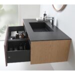 The Oslo 48 Inch Wall Mount Bathroom Vanity showcases a modern wood finish, black countertop, integrated sink, white faucet, and two open drawers for towels and toiletries—with natural light streaming in from the left.
