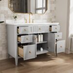 A modern Aveline 48 Inch Freestanding Bathroom Vanity With Top features a white countertop, gold faucet, multiple open drawers and cabinets, light gray finish with gold handles, set against brown floor tiles and a large mirror in the background.
