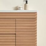 The Linea 48 Inch Wall Mounted Bathroom Vanity features a modern wooden design with horizontal grooves, complemented by a white countertop displaying a small jar and beige soap dispenser against a light-colored wall.