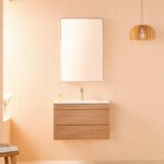 Minimalist bathroom with soft beige walls, a Linea 30 Inch Wall Mounted Bathroom Vanity and sink, large rectangular mirror, gold faucet, reed diffuser on the vanity top, and a hanging wooden light fixture.