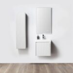 Minimalist bathroom with the Positano 20 inch Wall Mount Vanity With Sink, a coordinating wall cabinet, rectangular mirror, and wood floors. The vanity holds a soap dispenser, toothbrush holder, and small bottle.