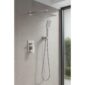 The Quadra Pressure Balanced Wall Mount Shower System features a large square overhead showerhead, a handheld attachment, and brushed metal controls, installed against light gray tiles beside a glass window.