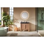 Modern bathroom with beige walls, a round backlit mirror above the Munich 36 Inch Bathroom Vanity with Top, a plant by the window, a freestanding bathtub, glass-enclosed shower, and a patterned rug on the floor.