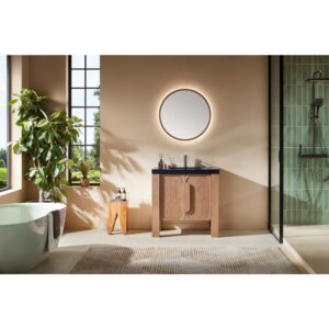 Modern bathroom with beige walls, a round backlit mirror above the Munich 36 Inch Bathroom Vanity with Top, a plant by the window, a freestanding bathtub, glass-enclosed shower, and a patterned rug on the floor.
