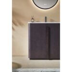 The Parma 36 Inch Bathroom Vanity With Top showcases a dark brown cabinet, white countertop, illuminated round mirror above, and small accessories on the counter against a beige wall.
