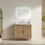 The Liora 30 Inch Bathroom Vanity features a light wood cabinet, white countertop, gold faucet, two small bottles, and a large illuminated rectangular mirror on a neutral wall, with shelves and a plant in the background.