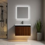 Modern bathroom featuring the Lille Wall Mounted Bathroom Vanity, a square illuminated mirror above, black faucet, gray potted plant, and a shower with a glass door on the left.