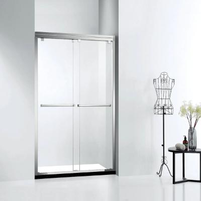 A modern glass shower door with a chrome frame and towel bars is installed in a white bathroom, styled like a kitchen and bath showroom. Nearby, a decorative wire dress form and a small table with flowers and bottles add a chic touch.