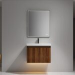 The Lille Wall Mounted Bathroom Vanity features a wooden cabinet with a white sink, black faucet, and rectangular mirror. Mounted on a gray wall, it is accented by warm under-cabinet lighting for a modern touch.