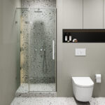 Modern bathroom with a Nova Hinged Frameless Shower Door enclosing terrazzo walls and floor, wall-mounted toilet, toilet paper holder, recessed shelf with toiletries, and neutral-toned walls and cabinetry.