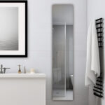 Modern bathroom featuring a white vanity, framed wall art, and the Royale 15 inch ×70 inch Side Tall Medicine Cabinet reflecting a glass shower. A black towel rack with white towels adds to the minimalist, clean decor.