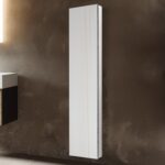 The Royale 15 inch × 70 inch Side Tall Medicine Cabinet with a white frame is mounted vertically on a brown textured wall in a modern interior space.