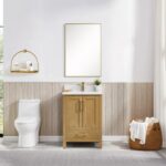 A modern bathroom with a white toilet, Basel 24 Inch Bathroom Vanity, sink, rectangular mirror, floating shelf with toiletries, towel basket, wood paneling, and a large window with white curtains.