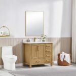 A modern bathroom highlights the Basel 36 Inch Bathroom Vanity with a white countertop, sink, and square mirror. To the left is a white toilet; to the right, a woven laundry basket sits by light wood paneling and a soft gray rug.