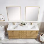 A modern bathroom features the Basel 72 Inch Double Bathroom Vanity with a light wood finish, white countertop, gold faucets, two square mirrors, a toilet to the left, plus toiletries and a plant on the counter.