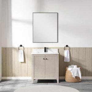 A minimalist bathroom features a rectangular mirror above the Torino 30 Inch Bathroom Vanity Cabinet in light wood, flanked by towel rings with white towels. A wicker basket with rolled towels sits on the tiled floor beside the vanity.