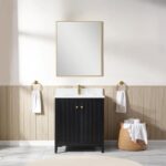 A modern bathroom features the Torino 30 Inch Bathroom Vanity Cabinet in black with a gold faucet and rectangular mirror above. Two white hand towels hang on gold rings, and a basket with rolled towels sits on wood-paneled flooring.