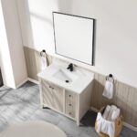 A modern bathroom features the Torino 36 Inch Bathroom Vanity Cabinet with drawers, a white countertop and sink, black faucet, large square mirror, towel rings with white towels, and a basket of rolled towels on gray tile flooring.
