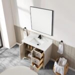 A modern bathroom featuring the Torino 36 Inch Bathroom Vanity Cabinet with drawers, open for display, paired with a black faucet, a square mirror, towel rings holding white towels, and a basket of rolled towels on a gray marble floor.