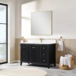 A modern bathroom features the Torino 48 Inch Bathroom Vanity Cabinet in black with gold knobs, a white countertop, a large gold-framed square mirror, and gold towel holders. Sunlight pours through a glass door; a basket of white towels sits nearby.