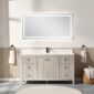 A modern bathroom showcases the Torino 60 Inch Single Bathroom Vanity with multiple drawers and a central cabinet, topped by a large illuminated mirror. Neutral, minimal decor includes towels on both sides and rolled towels on stools.