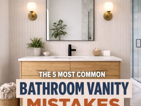 A modern bathroom with a wooden vanity, round mirror, wall sconces, and a woven hamper. Text overlay reads: The 5 Most Common Bathroom Vanity Mistakes We See In Showrooms. Avoid these common bathroom vanity mistakes when designing your space.